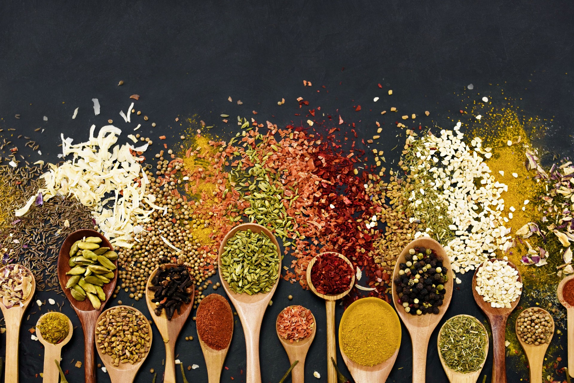 Colorful mix of herb and spice varieties: curry and coriander, turmeric and cumin, paprika and pepper, mustard and salt, cardamon and oregano and saffron